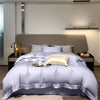 Luxuriöses Bettwäsche-Set mit lavendelfarener Decke und Kissen auf einem modernen Bett.