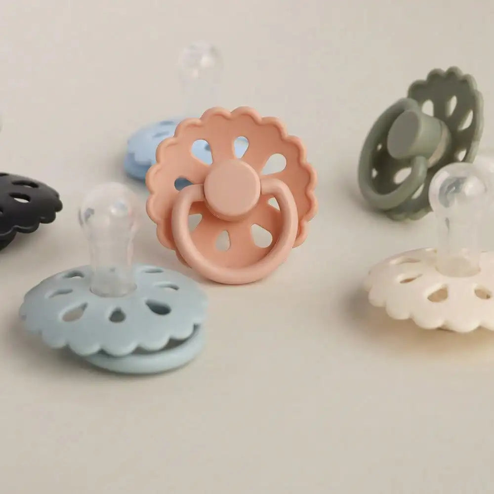 A collection of silicone baby pacifiers in various pastel colors including pink, blue, and green.