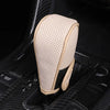 A beige perforated leather shift knob cover is shown placed inside a black gear shift.