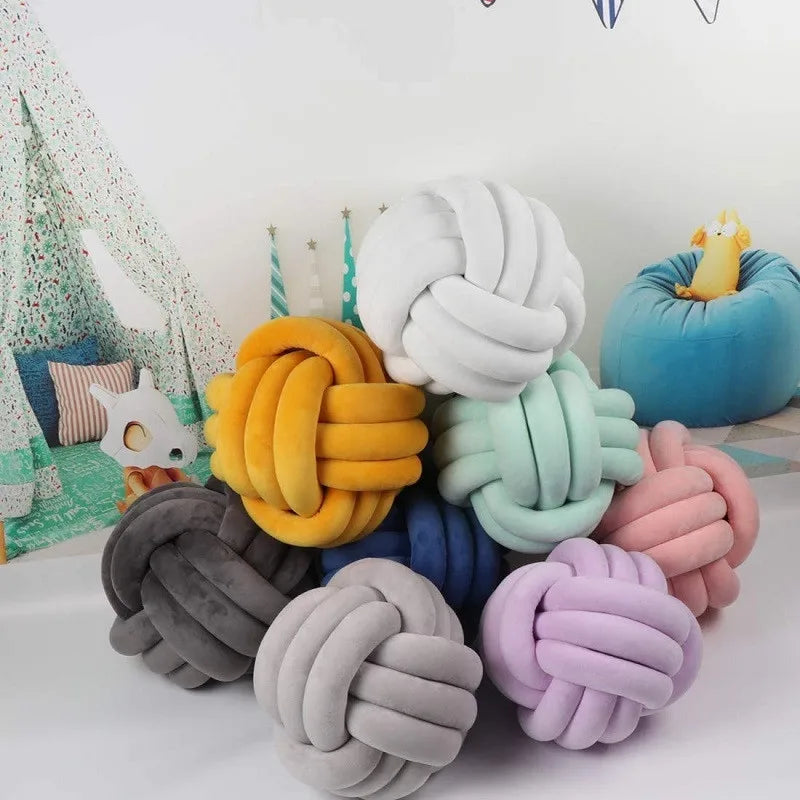 A collection of handmade knitted velvet throw pillows in various shades including yellow, white, green, blue, and pink.