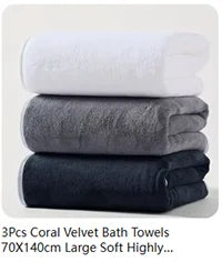 Three stacked coral velvet bath towels in white, gray, and navy blue.