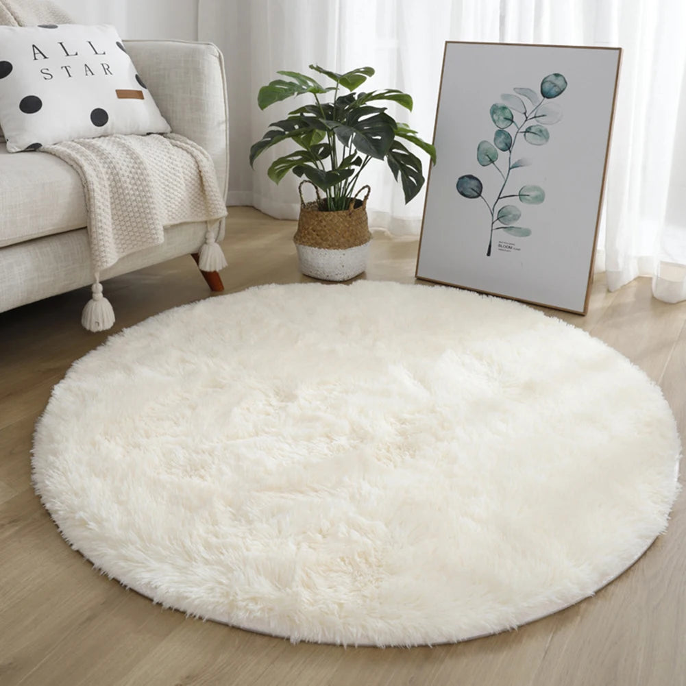 A fluffy white shaggy round rug placed on a wooden floor next to a potted green plant and a framed botanical print.