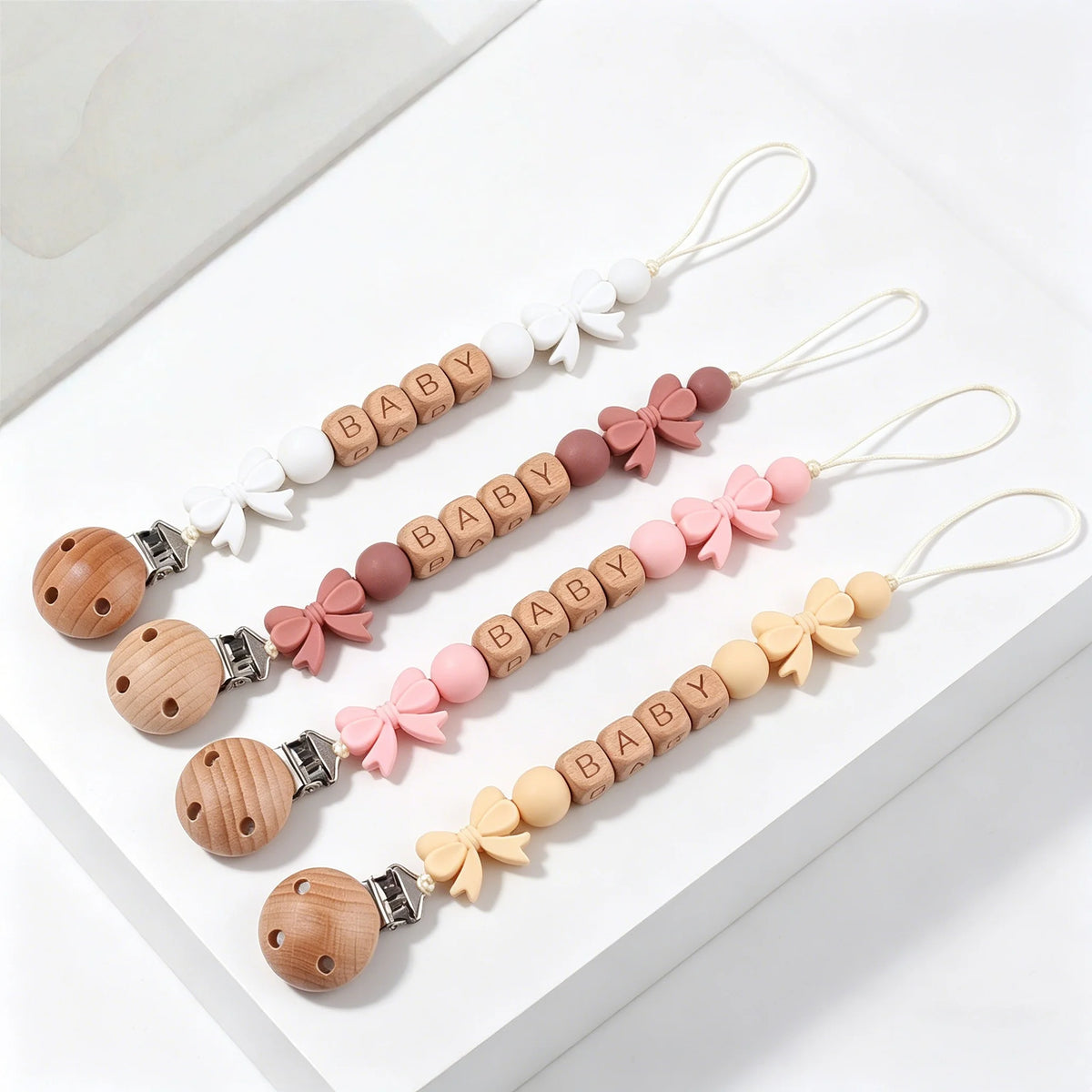 A set of personalized silicone pacifier clips with various floral designs and wooden beads on white lanyards.