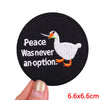 Black embroidered patch featuring a white duck with peace text on it
