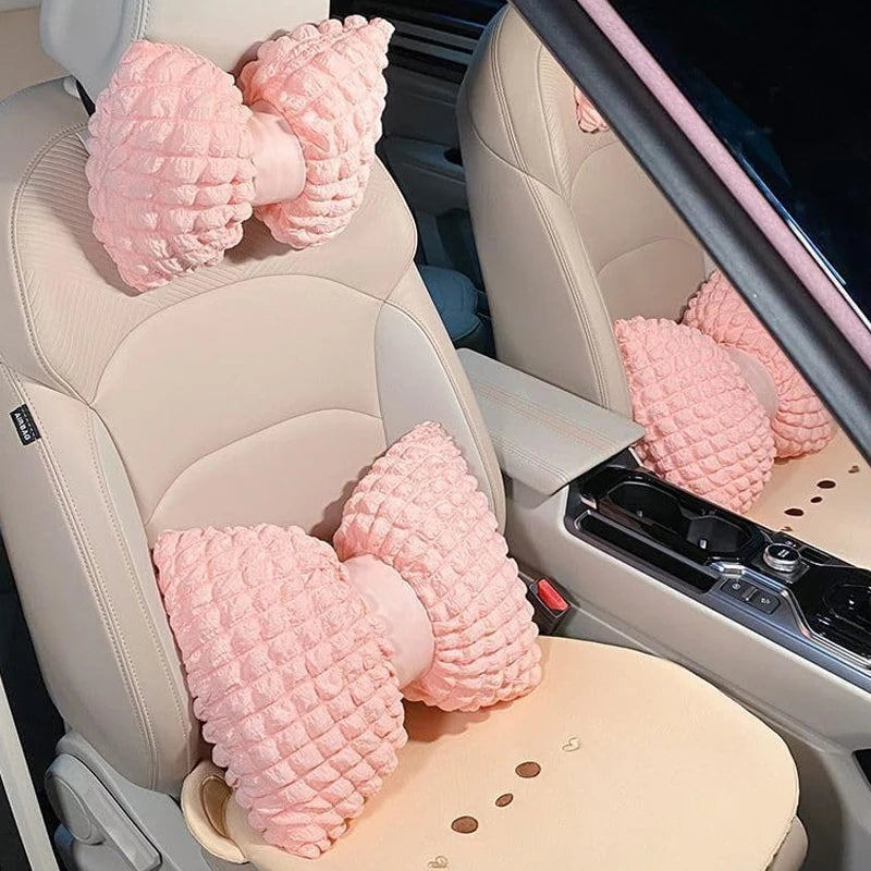 Pink bowknot car neck pillow with lumbar support placed in a car seat interior.