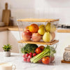 Stackable clear pantry storage bins with bamboo lids filled with fresh produce like apples and tomatoes