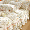 A set of floral ruffle cotton duvet covers in cream and beige tones displayed on a bed.