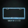 A rectangular crystal rhinestone license plate frame with two screw caps and various mounting hardware displayed on a dark ba
