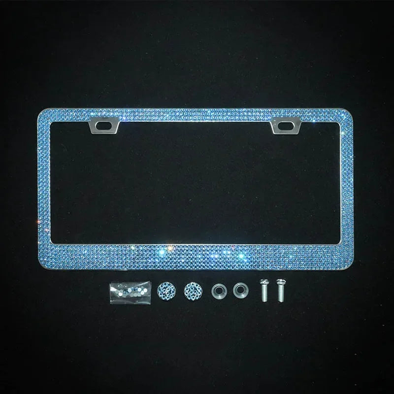 A rectangular crystal rhinestone license plate frame with two screw caps and various mounting hardware displayed on a dark ba