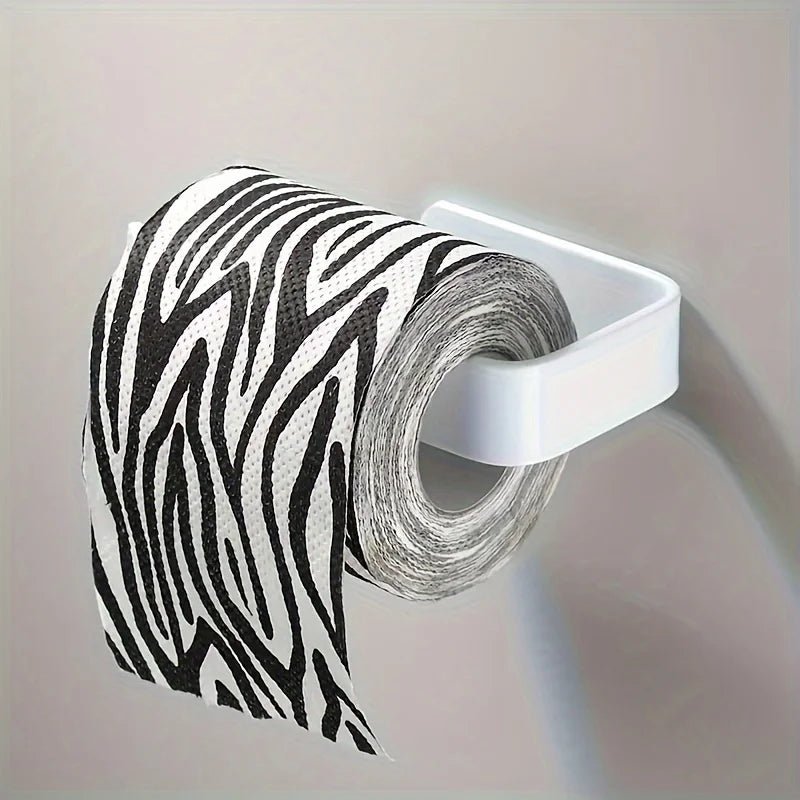 A roll of black and white zebra-print toilet paper is mounted on a white wall holder.