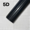 Close-up of a glossy black carbon fiber vinyl wrap film showing a diagonal weave pattern on a sheet of graph paper.