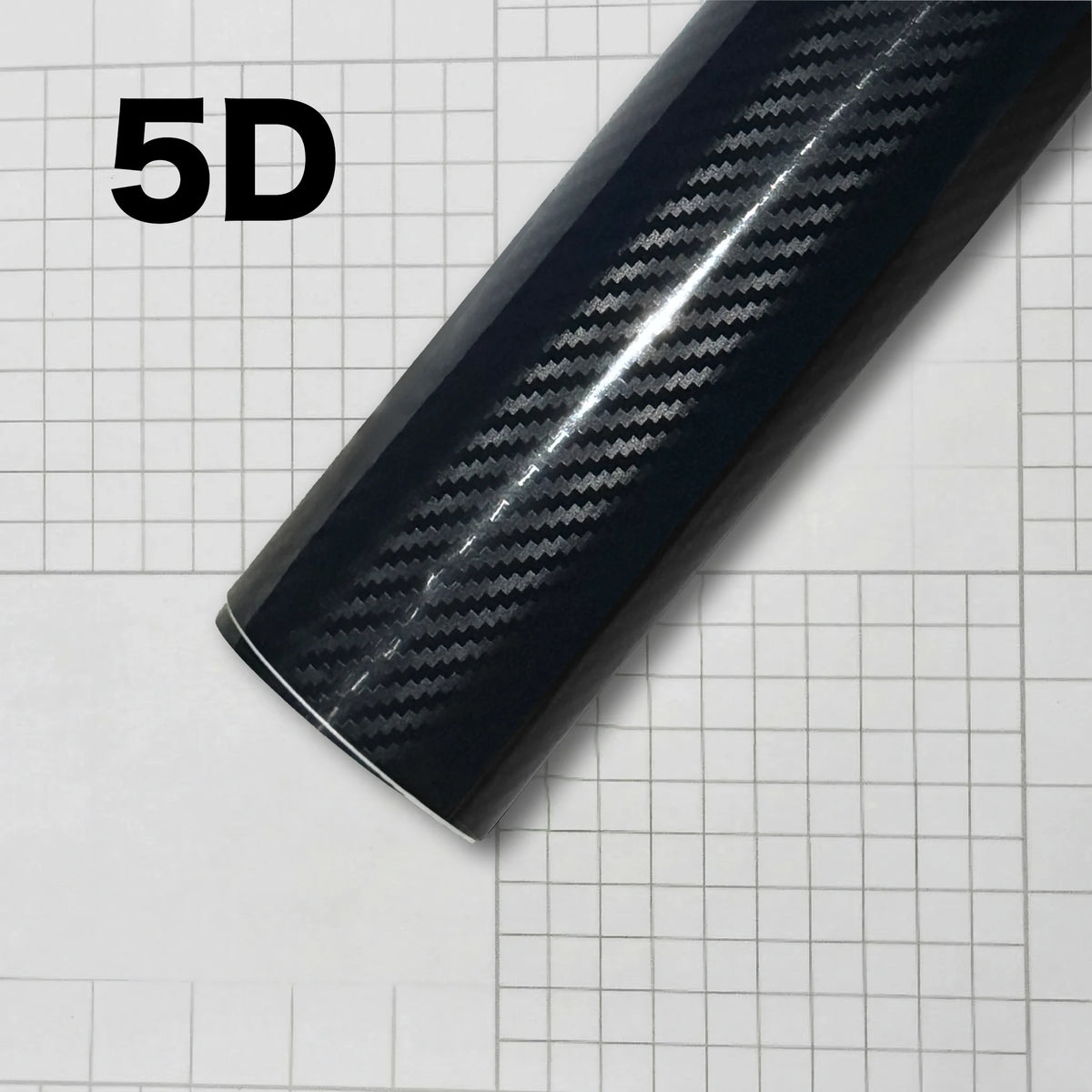Close-up of a glossy black carbon fiber vinyl wrap film showing a diagonal weave pattern on a sheet of graph paper.