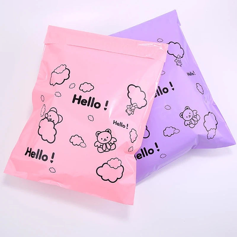 Two pink and purple self-sealing mailing bags featuring a hello cloud bear design
