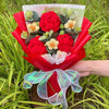 Ein Strauß roter Häkelblumen und grüner Belaubung, in rohem Papier eingewickelt und mit einem durchsichtigen grünen Band gebu