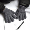 A pair of dark gray, fuzzy plush winter gloves resting on a piece of white paper.