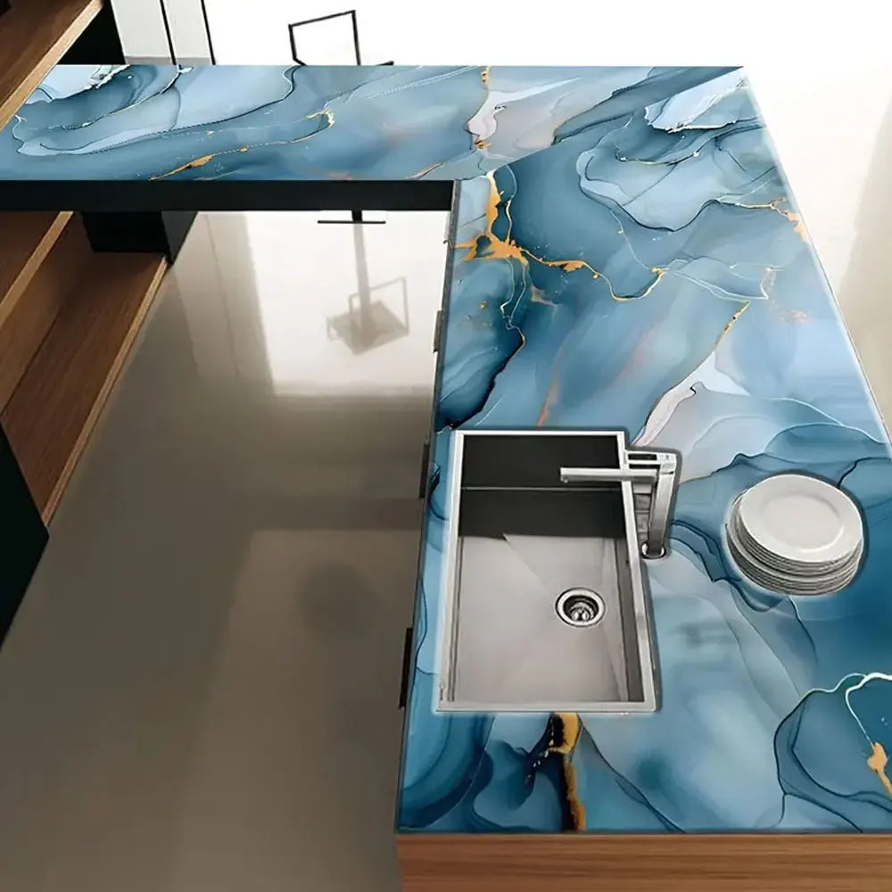 A kitchen countertop featuring blue marble peel-and-stick wallpaper with gold veining and a stainless steel sink.