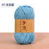 A ball of light blue cotton blend crochet yarn is shown on a wooden surface.