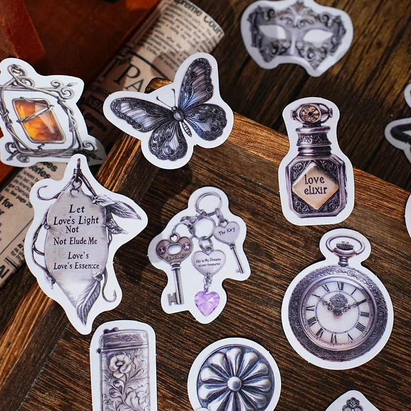 A collection of vintage alchemy washi stickers featuring metal-embossed designs like a flask, key, and clock on a wooden surf
