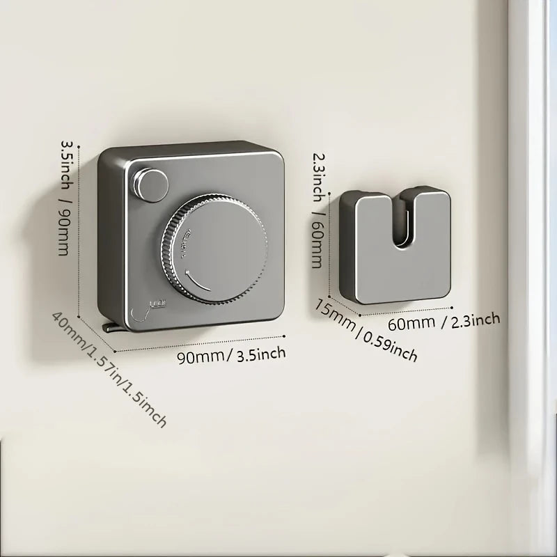 A silver retractable clothesline with a circular handle and storage mechanism mounted on a white wall.