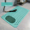 A teal non-slip bath mat with massage nodes and a small black tool is displayed on a light gray floor.