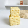 A stack of yellow cheese squishy stress relief fidget toys resting on a white surface.