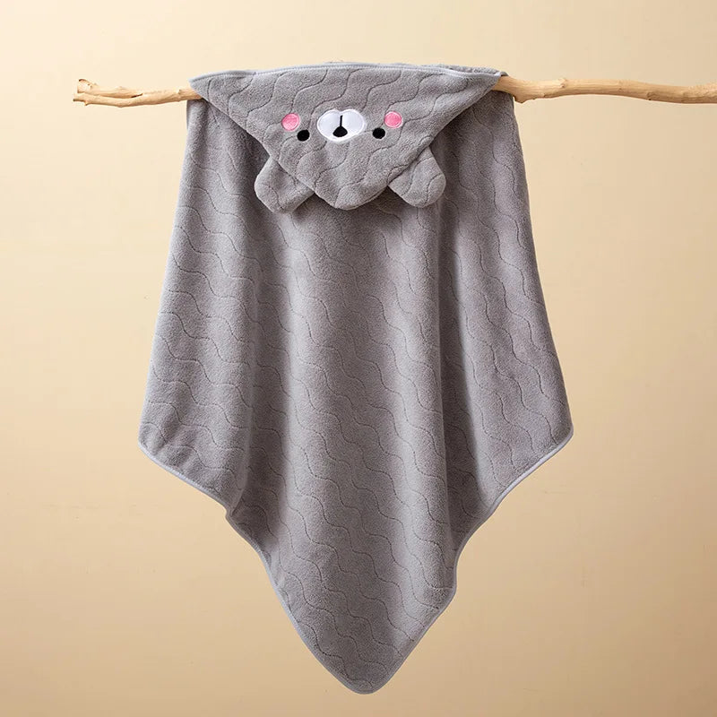 A gray hooded baby bathrobe towel with a cute bear face design hanging on a wooden stick.
