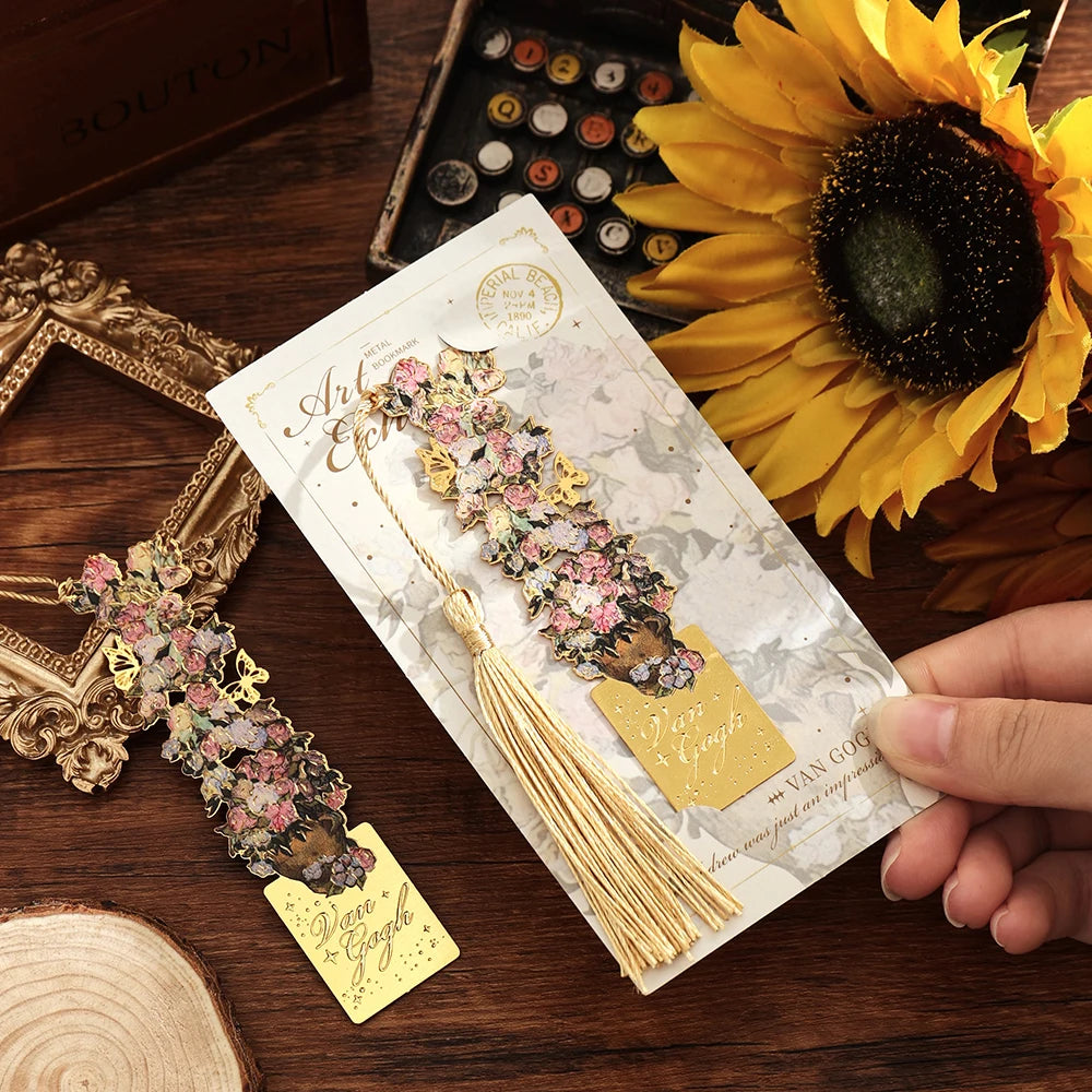 A hand holds a vintage metal bookmark with an artistic hollow design and tassel against a dark wooden background and a sunflo
