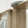 A flexible microfiber duster with a grey fuzzy head is shown resting on a wooden cabinet shelf.