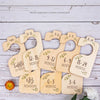A set of eight wooden baby closet dividers labeled with months, ranging from newborn to 24 months, displayed on a white woode