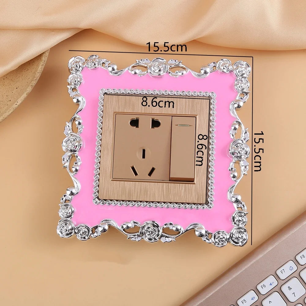 A rectangular switch cover frame with a rose pattern border and brass finish, shown against a light background.