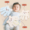 A baby is resting while using various soft, palm-shaped pressure tools on their arms and belly.