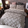 A beige quilted comforter and matching pillowcases are displayed on a bed with dark wood accents.