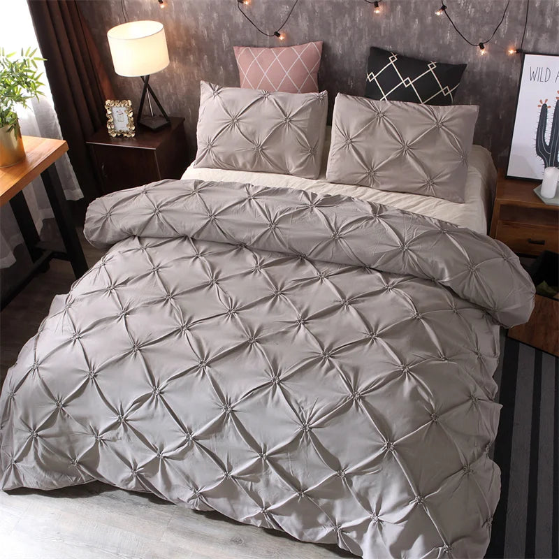 A beige quilted comforter and matching pillowcases are displayed on a bed with dark wood accents.