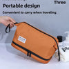 An orange handheld portable toiletry bag is being held by a hand, demonstrating its convenient design for traveling.