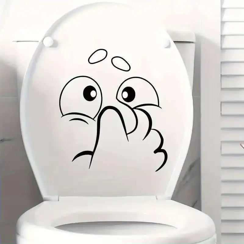A white toilet lid features a black sticker depicting an expressive, surprised face.