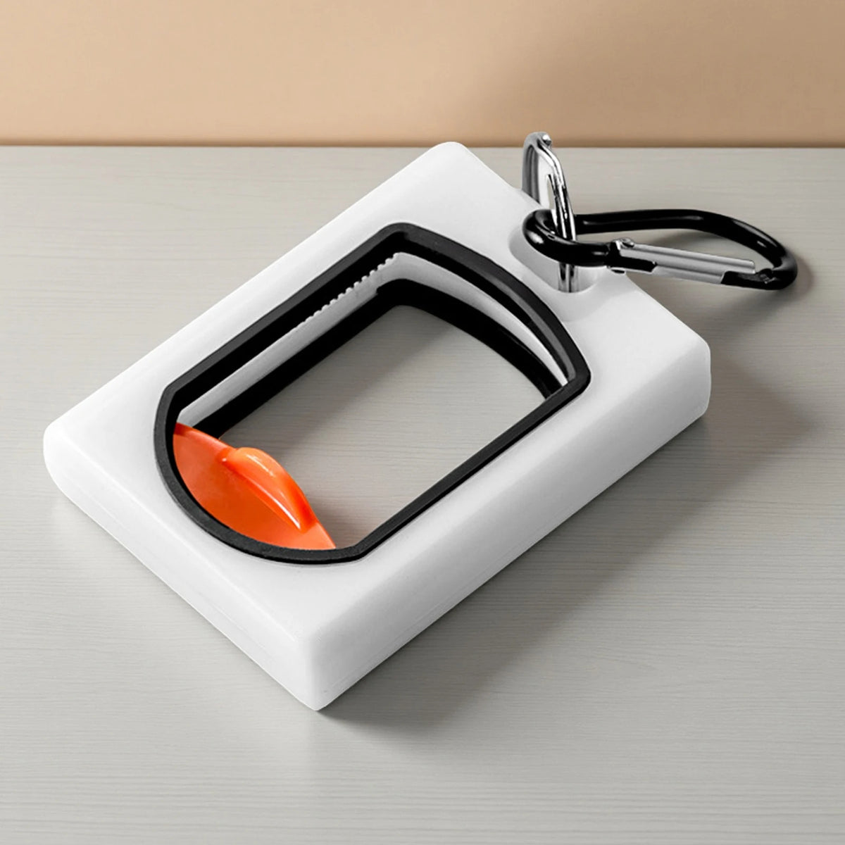 A white organizer tray holds a black cable tie with an orange tip and a silver carabiner clip.