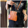A woman holds a vintage brown PU leather crossbody handbag against a black t-shirt.