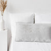 A white linen pillowcase with an envelope closure resting on a white bed.