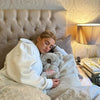 A person is relaxing in a bed with a large stuffed koala plush companion next to them.