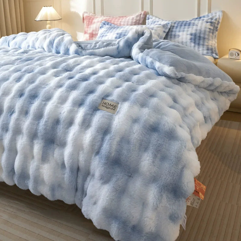 A light blue plush winter comforter with a quilted texture is displayed on a bed.