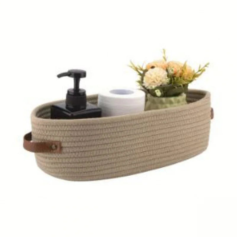A woven cotton rope storage basket with a black lid and a white roll of paper inside.