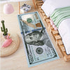 A runner rug featuring a design of a US hundred dollar bill on a wooden floor next to a bed.