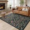 A vintage floral area rug featuring dark green and pink botanical patterns in a living room setting.