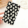 A black card holder with a white heart pattern is shown against a white background next to a woven basket.