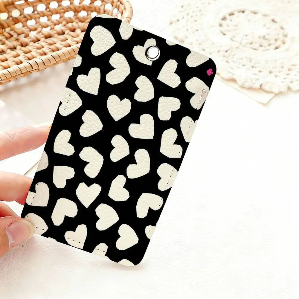 A black card holder with a white heart pattern is shown against a white background next to a woven basket.