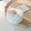A white microfiber wrist sweatband and scrunchies for face washing resting on a light wooden tray.