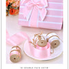 Pink double-face satin ribbon rolls tied with twine and presented in a gift box.