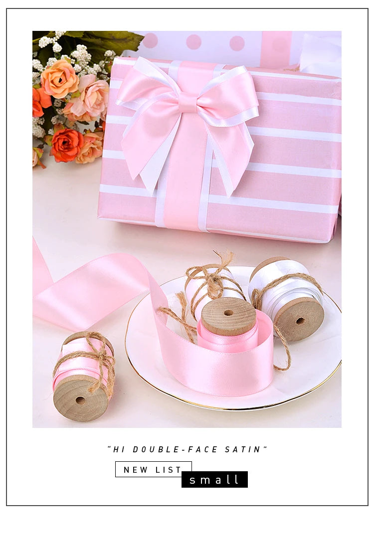 Pink double-face satin ribbon rolls tied with twine and presented in a gift box.