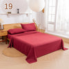 A deep red bedding set featuring a fitted sheet, flat sheet, and pillowcases displayed on a bed in a bright room.