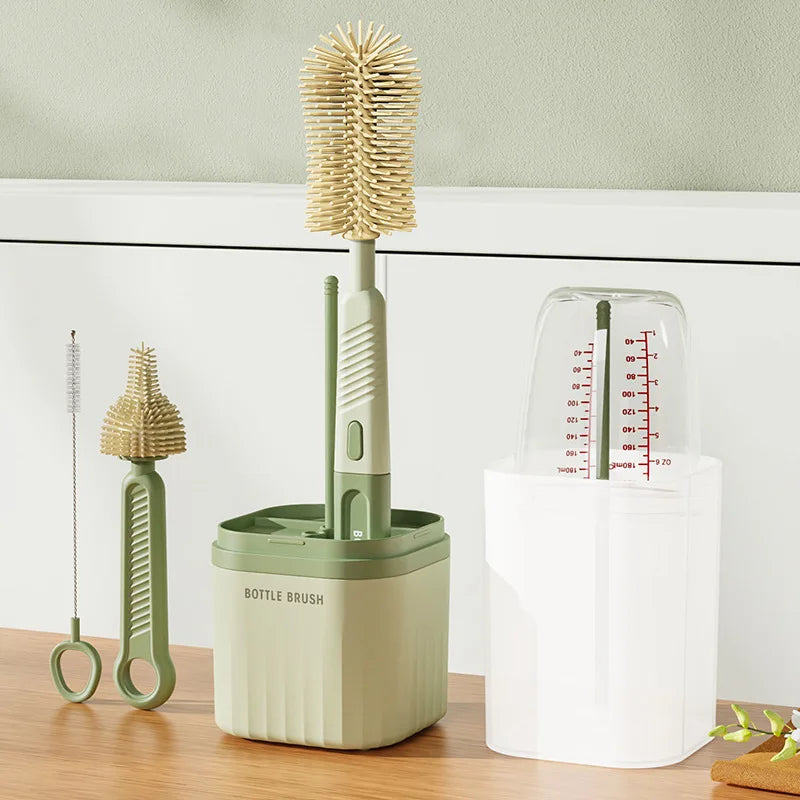 A silicone baby bottle brush set with a green handle and a rotating head is shown next to a white drying rack.